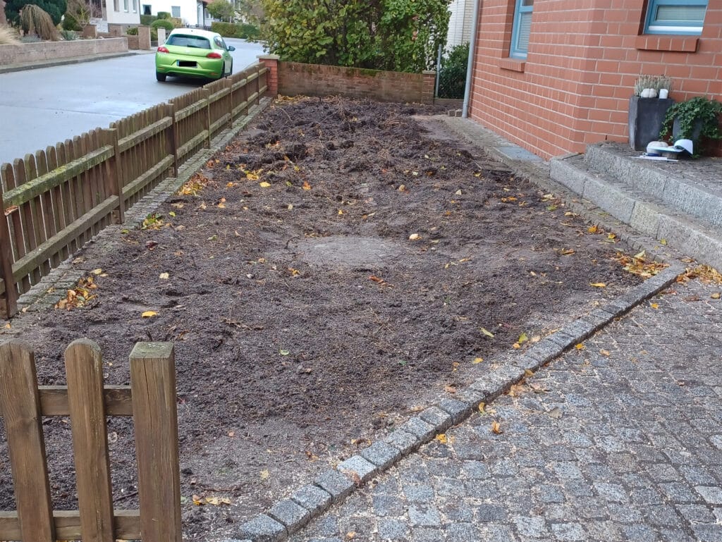 umgegrabenes, nicht bepflanztes Beet, umgeben mit einem Holzzaun